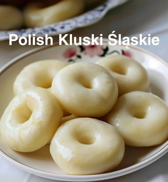 Kluski Śląskie podane na talerzu z sosem i dodatkami